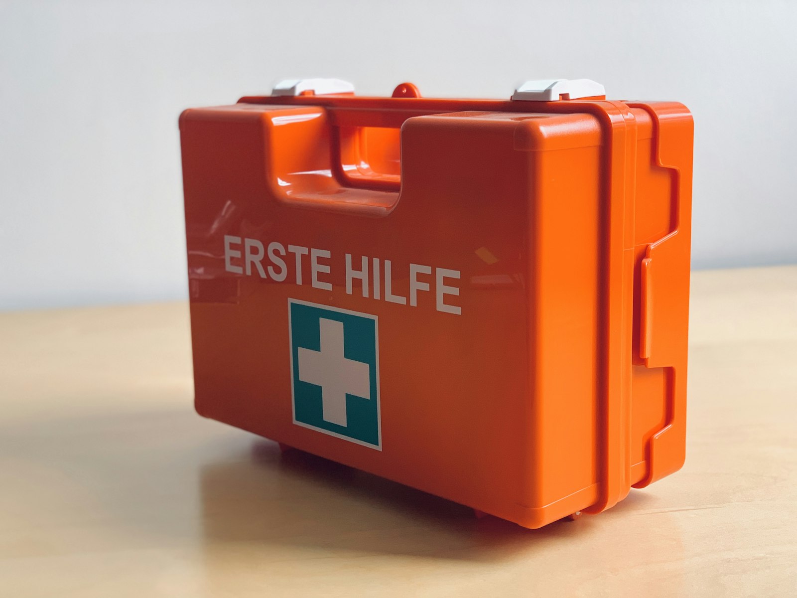 Orange first aid box mounted on a plain wall labelled ERSTE HILFE